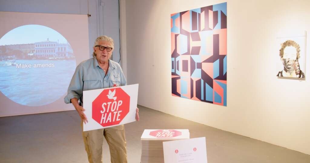 A man holds a sign that says "stop sign" during a moment from "Art Not as Usual."